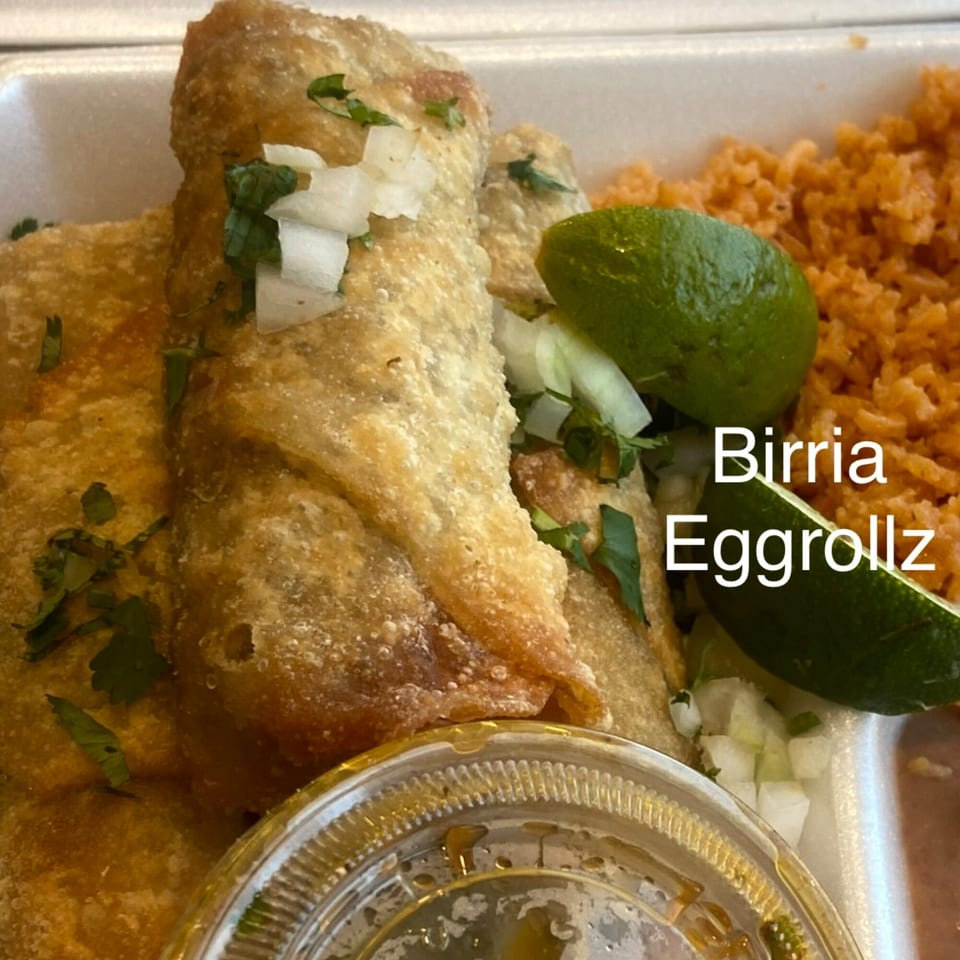 Crispy Birria Eggrollz with rice, lime, and a side of dipping sauce from Vaqueros Over the Fire.