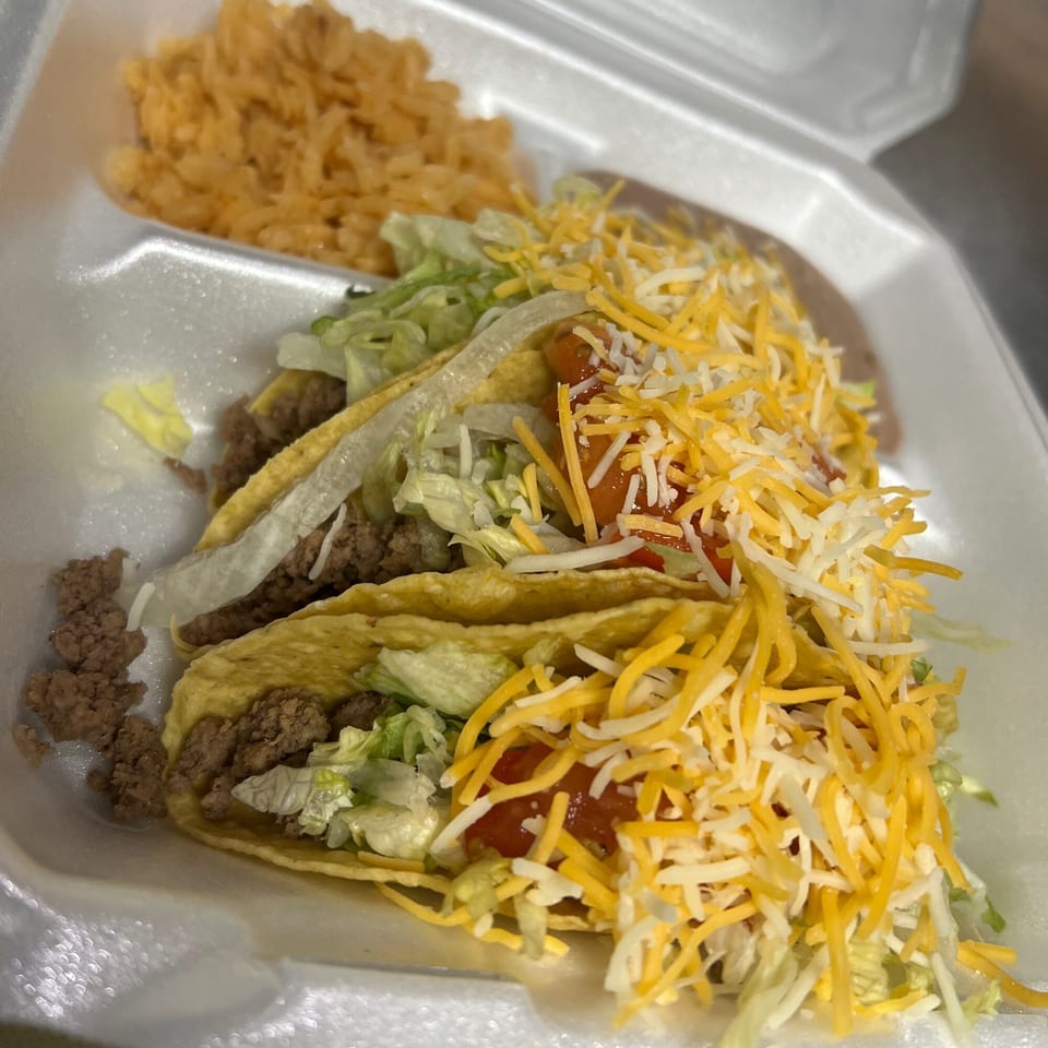 Three Vaqueros Over the Fire tacos with ground beef, lettuce, cheese, and salsa, served with rice.